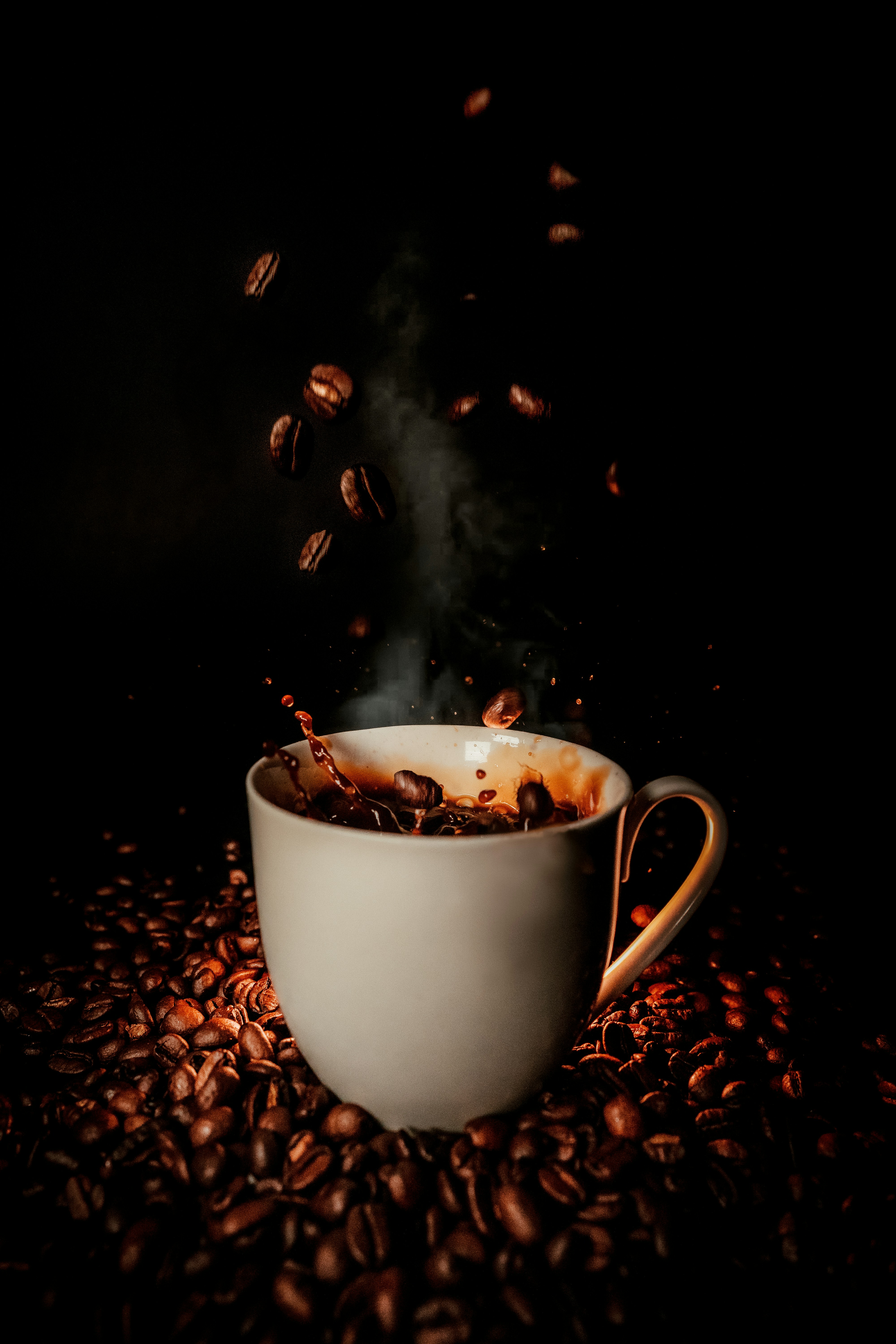 white coffe cup with splash of coffee and coffee beans
